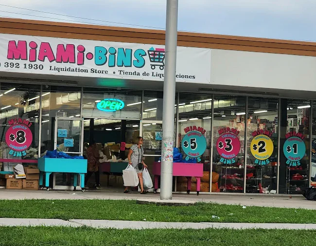 Miami bins physical location showing their logo and a customer walking out with full bags of purchases. 